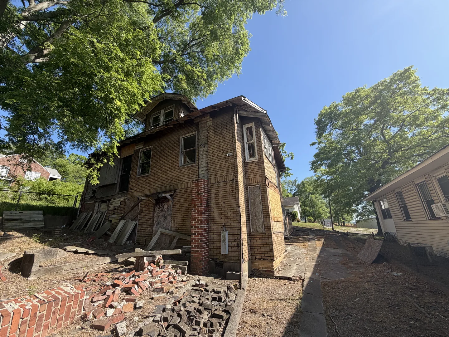 The second house on the same job before work, its asphalt siding coming away in sheets and salvaged brick stacked against the wall