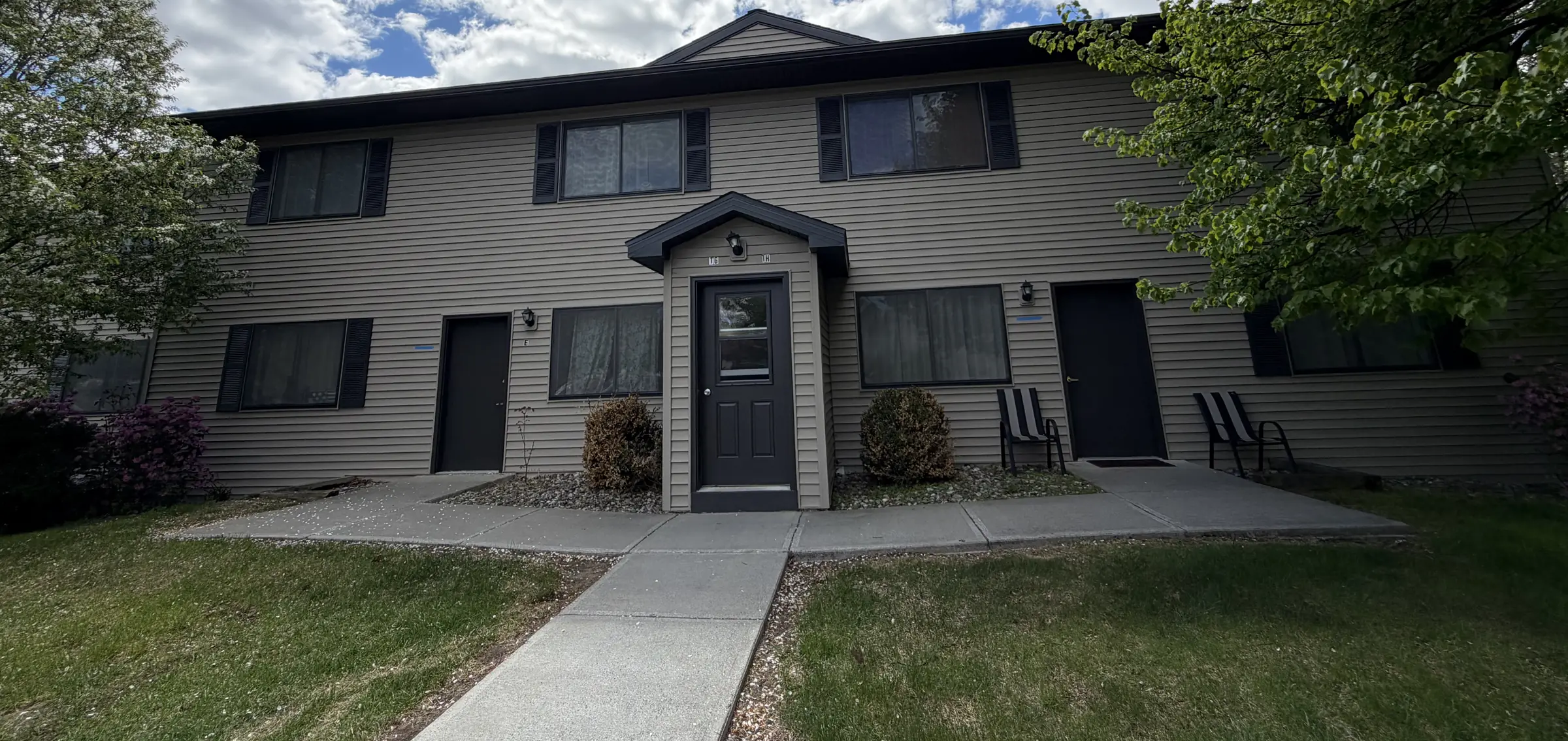 A four unit building at McGregor Village after exterior work, with a centred gabled entry hood and black shutters