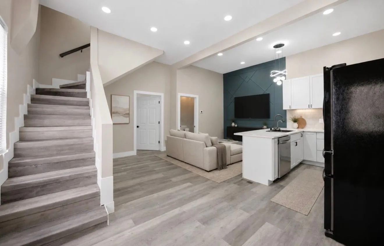 An open living space in a second unit, seen from the stair, with a teal panelled wall and the kitchen beyond